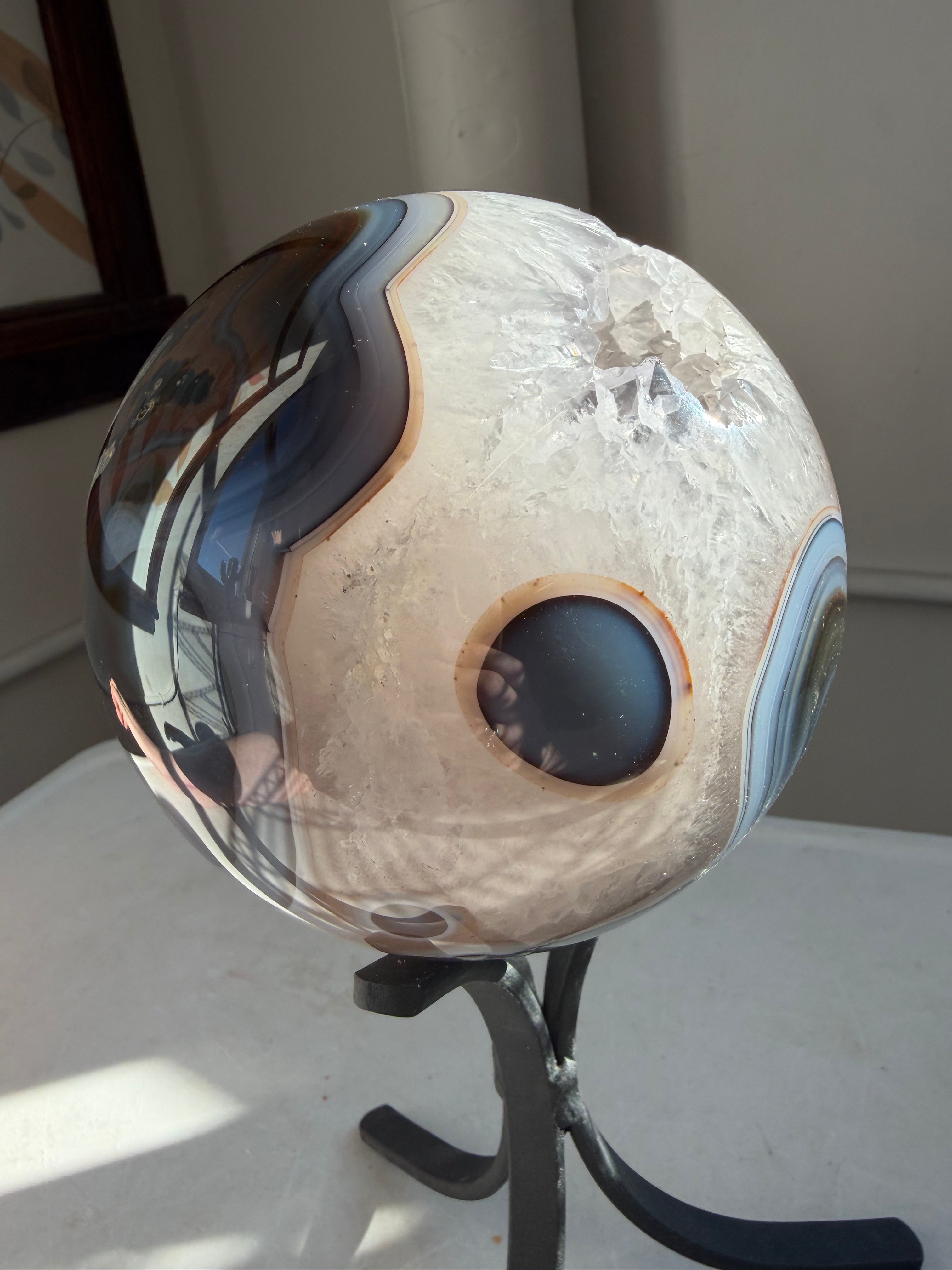 crystal agate sphere, with reds and blues with natural portal on stand
