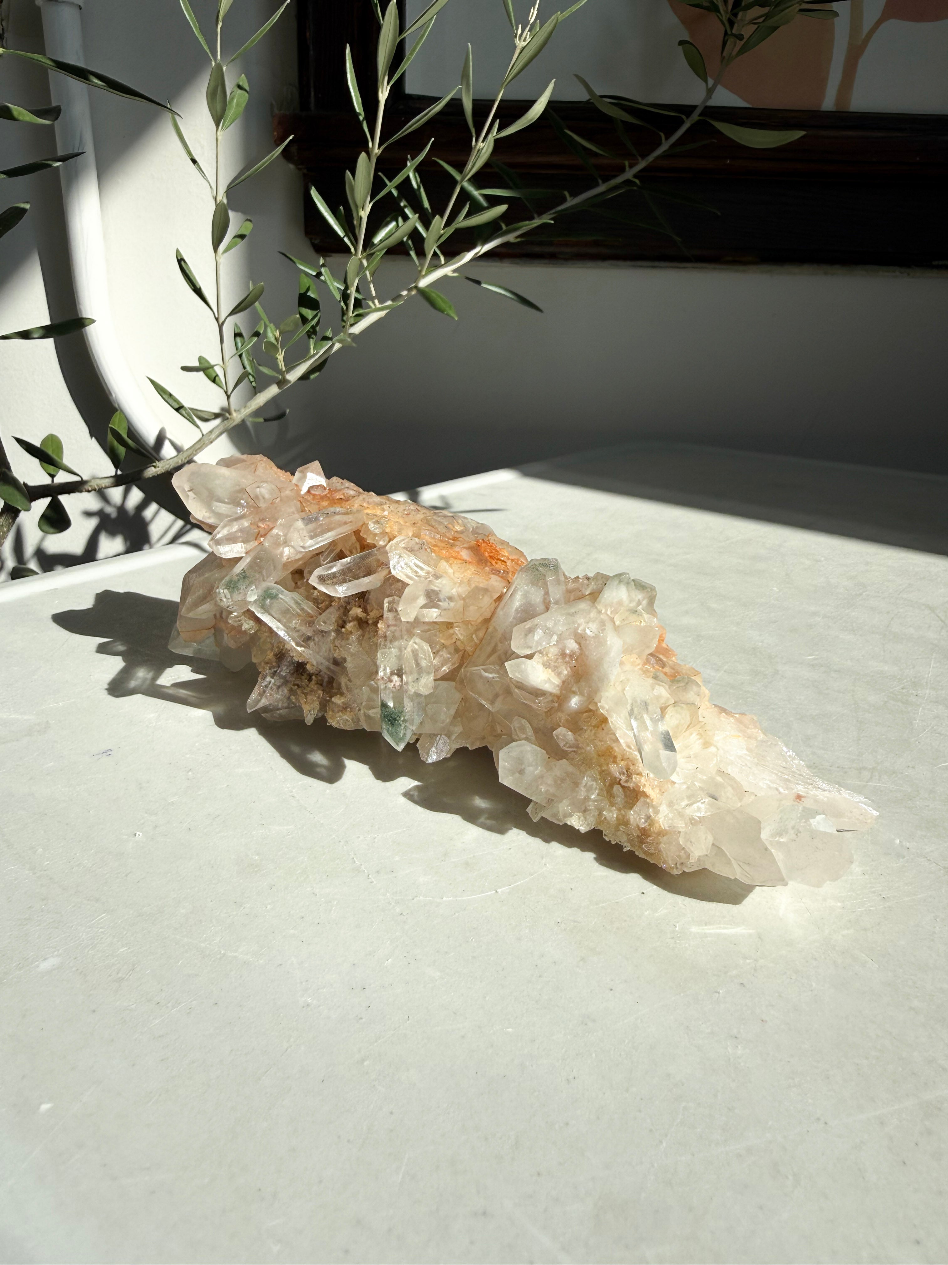 Chlorite and iron inclusions quartz cluster on white marble counter