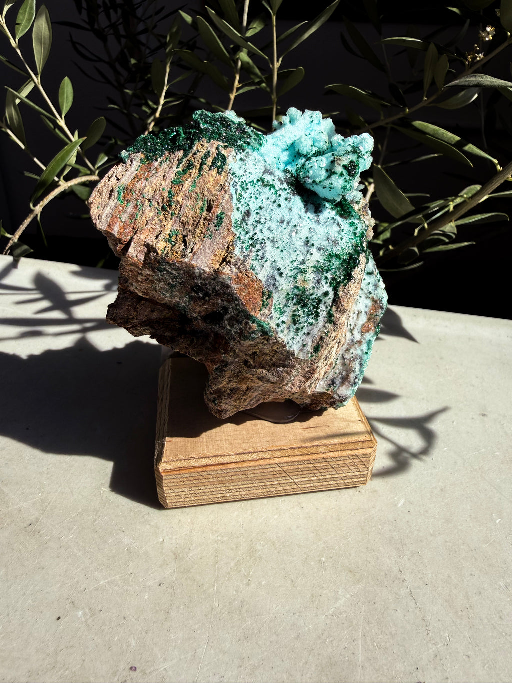 Chrysocolla, Barite, Quartz, Malachite mounted on a wooden base on whote marble countertop