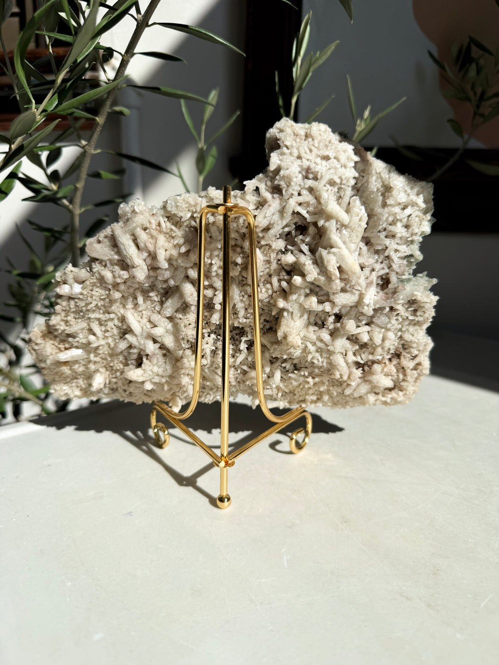 gold stand on marble counter holding Chlorite and quartz cluster