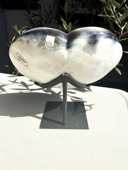 polished orca agate heart with a yellow druzy center on a custom stand