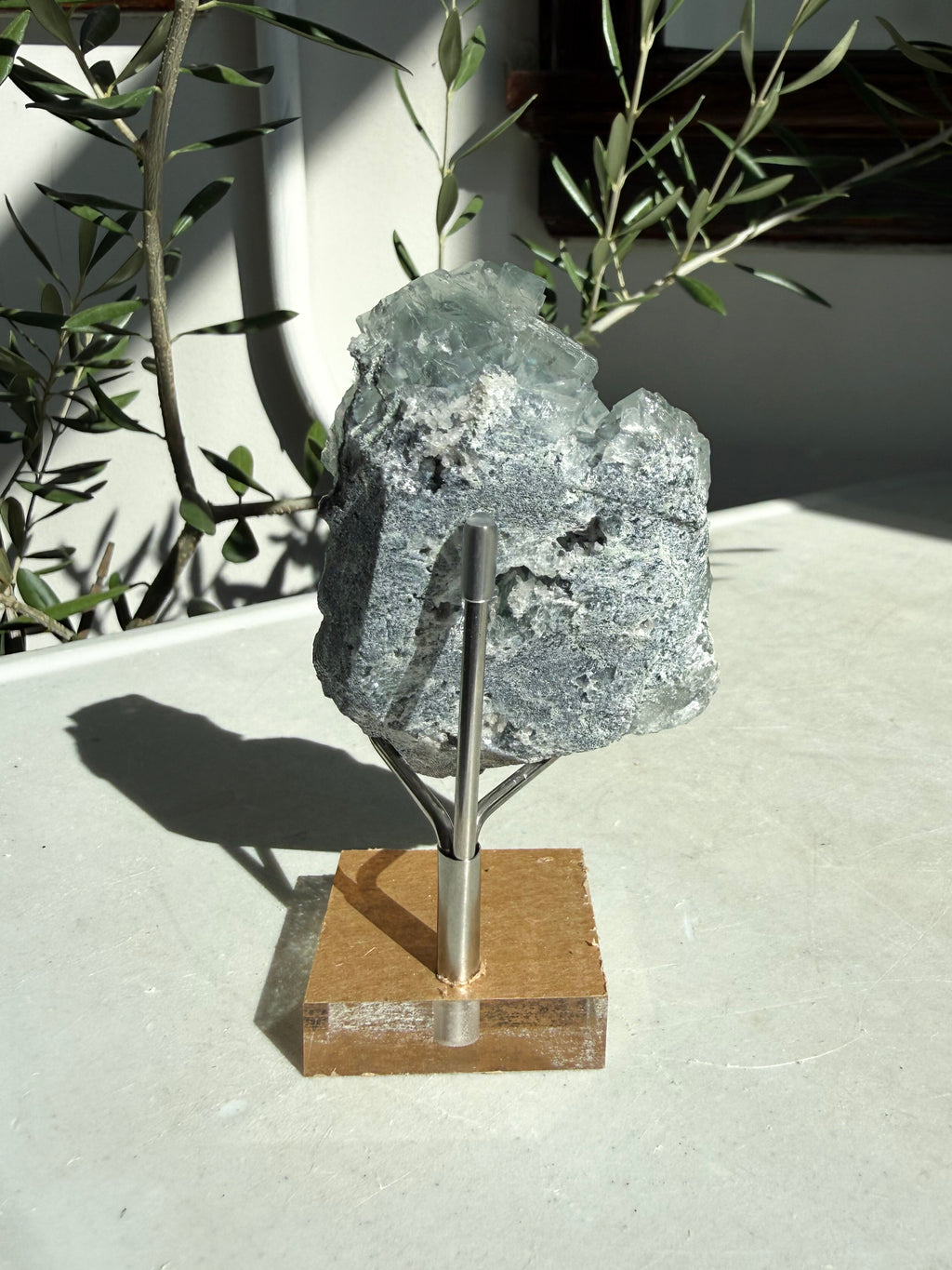 Glassy green cubic fluorite with druzy quartz sitting on marble table