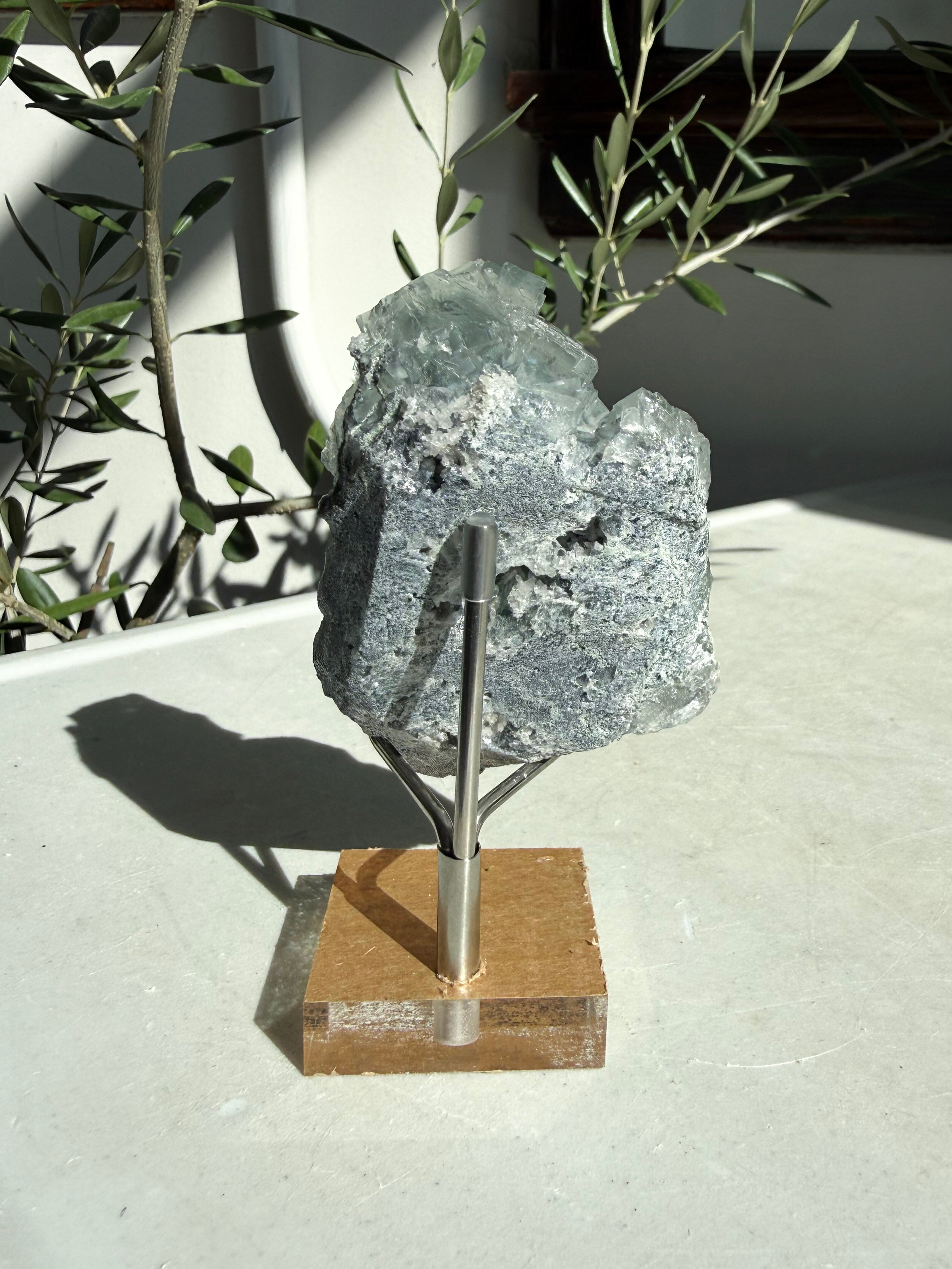 Glassy green cubic fluorite with druzy quartz sitting on marble table