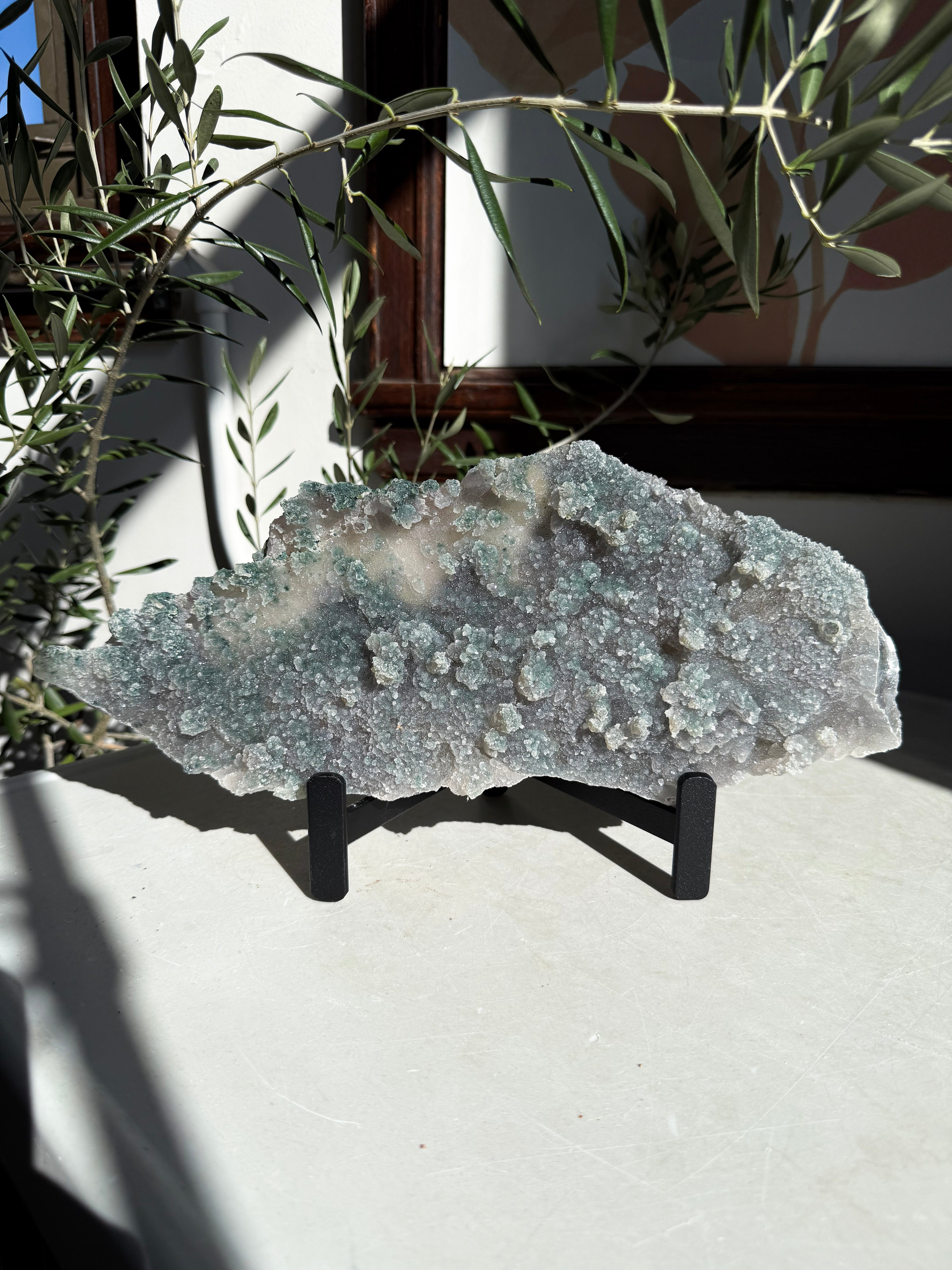 emerald green amethyst flower plate on metal stand sitting on white marble table. 
