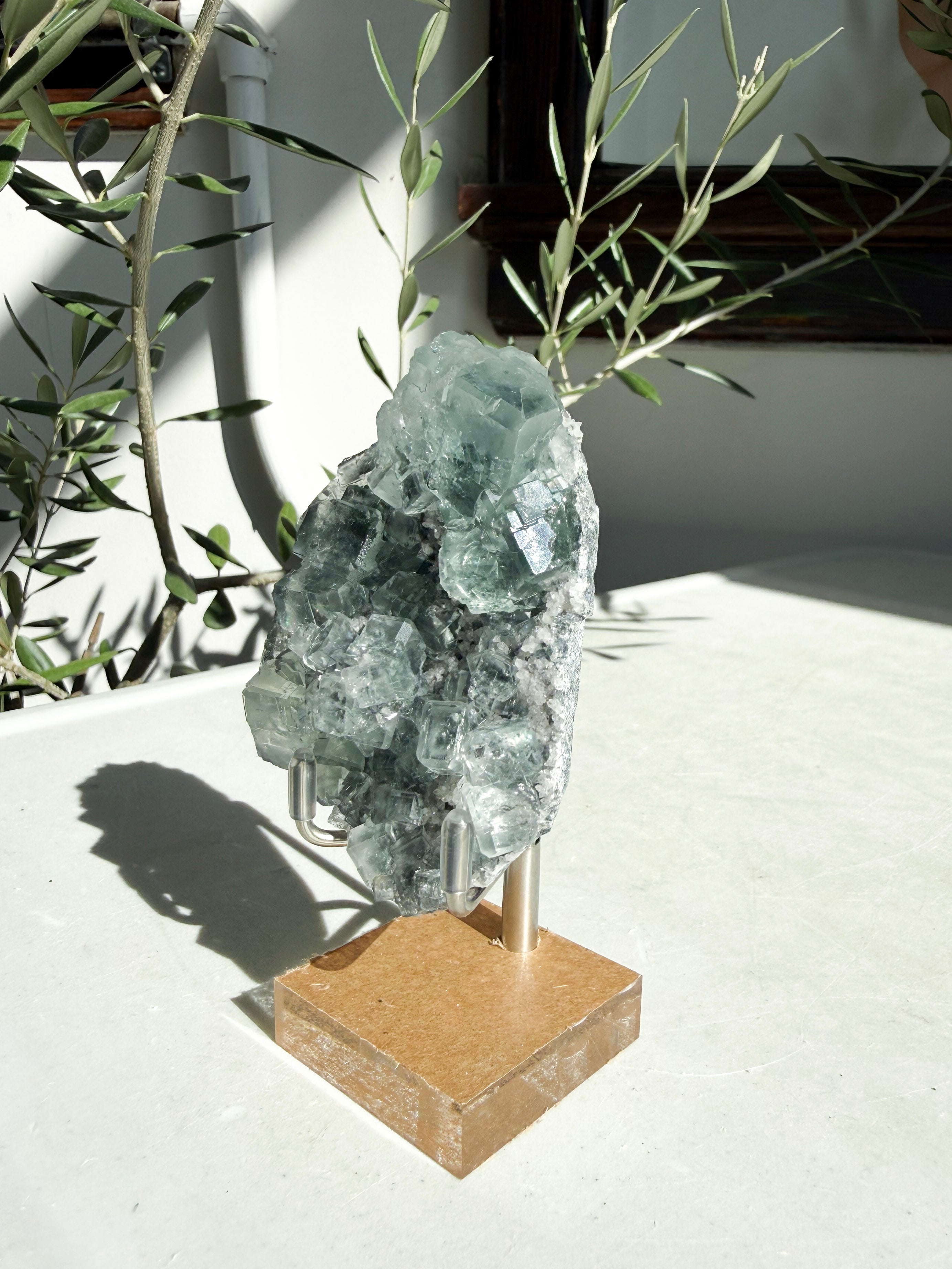 fluorite with druzy quartz on wood stand sitting on marble table