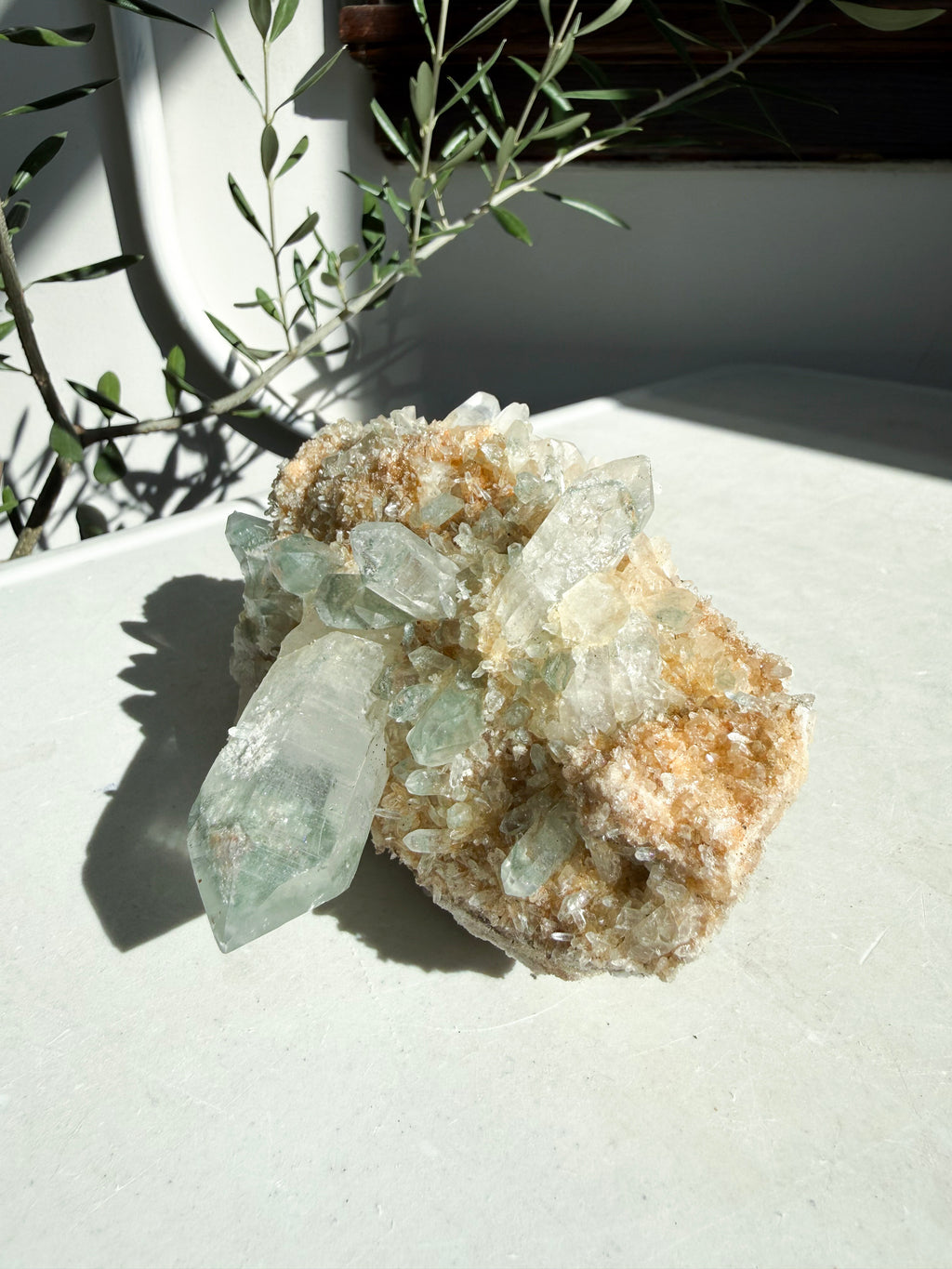 Indian Chlorite Quartz Cluster with iron inclusions on white marble counter