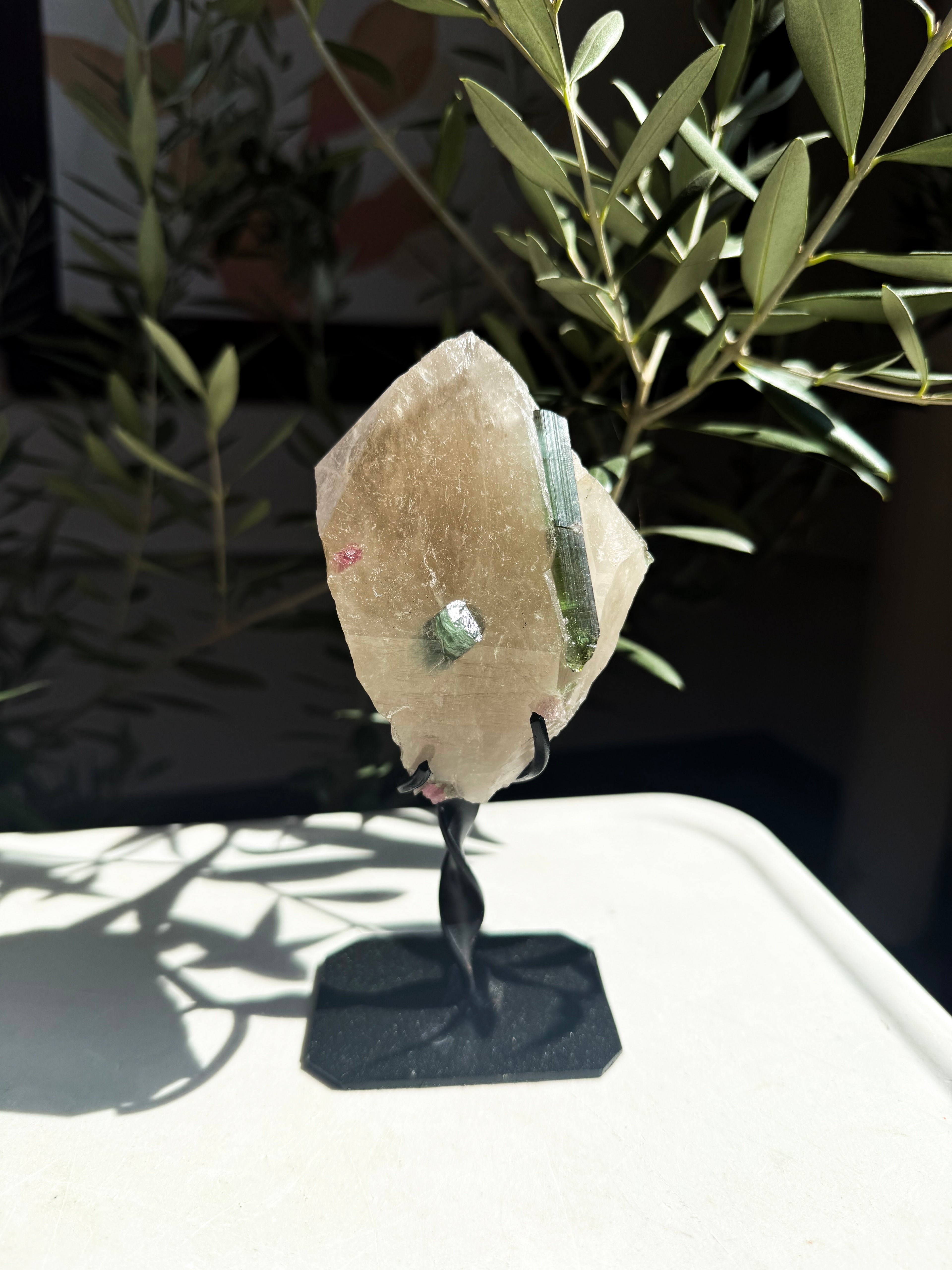 close up of natural citrine matrix with blue tourmaline on metal stand resting on white counter