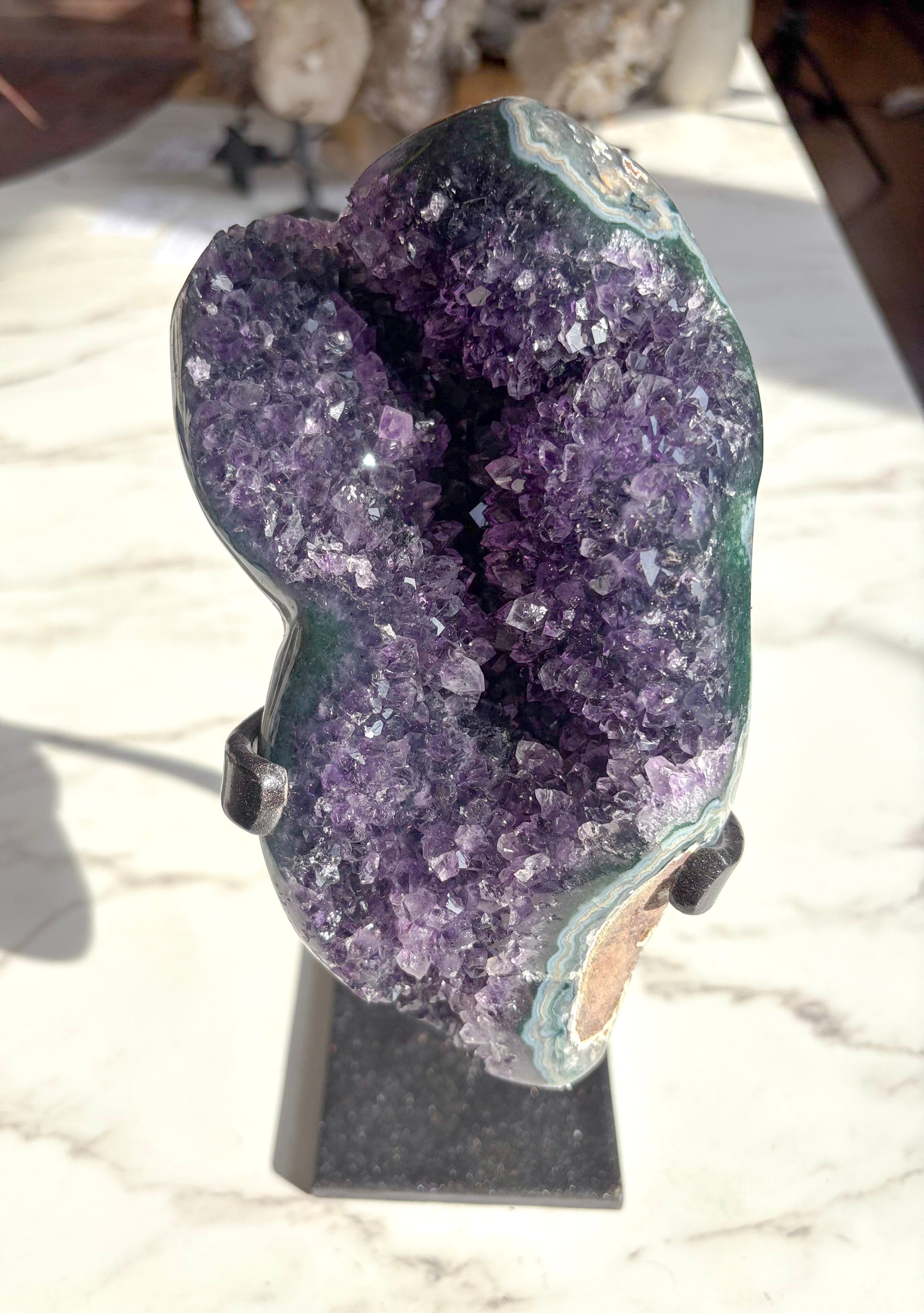 raw amethyst mineral with polished green agate banding on the edges on white countertop