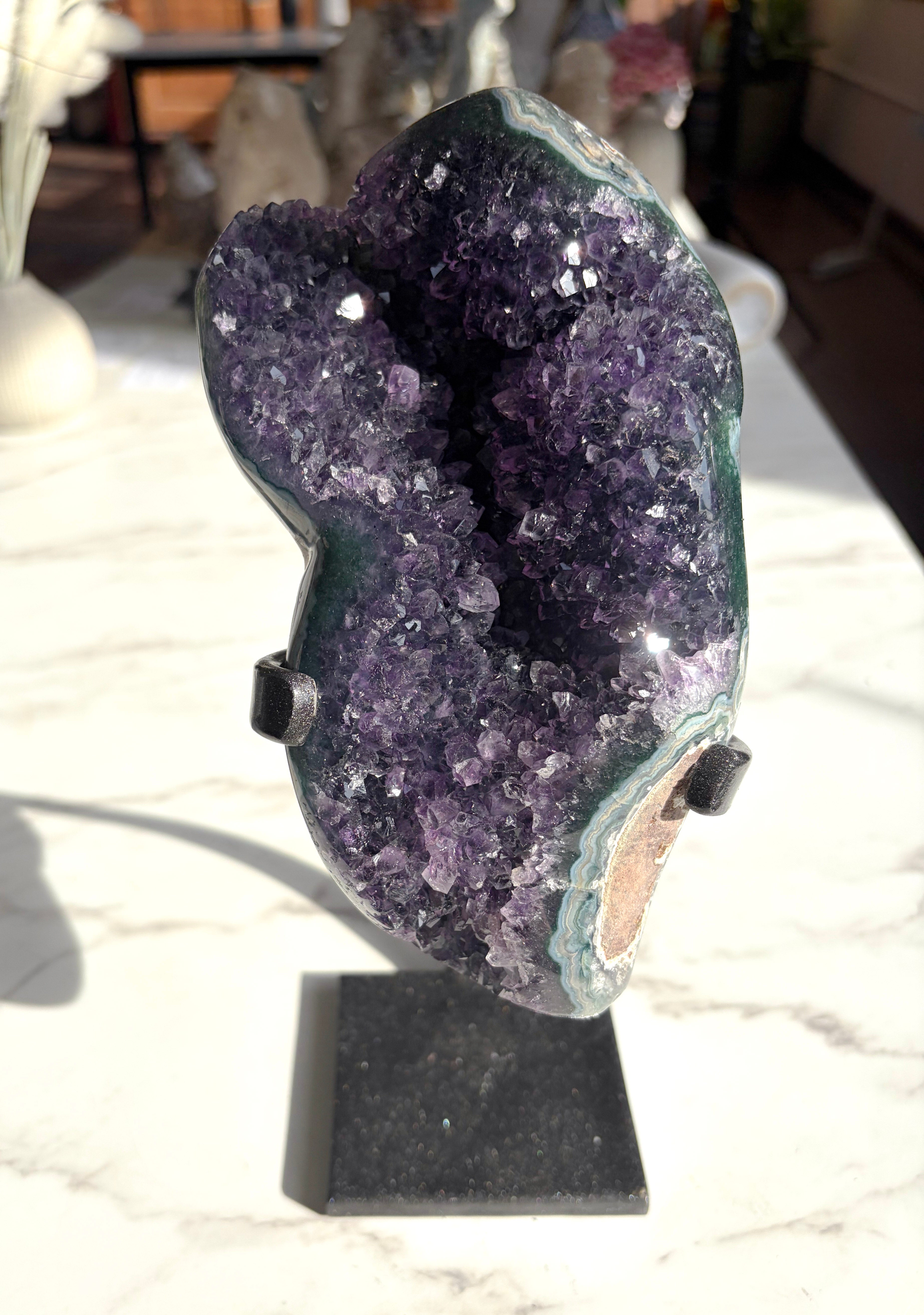  amethyst crystal with polished green agate banding on the edges on white countertop