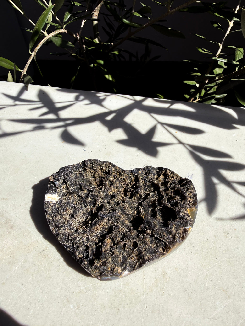 dark gray raw druzy in heart shape on white background with shadow