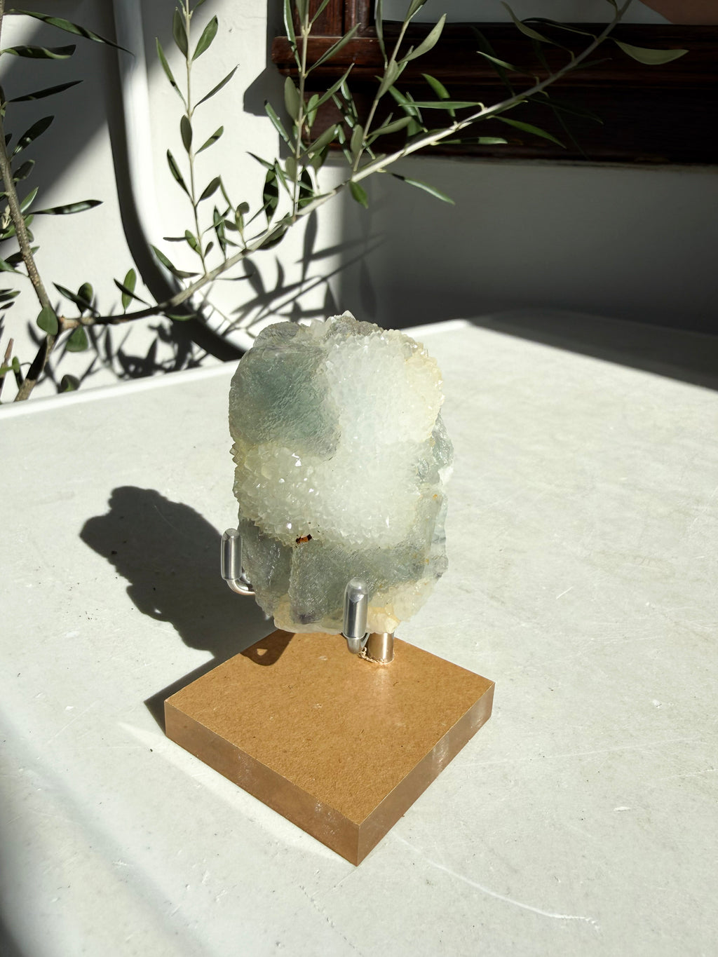 fluorite druzy quartz on wooden and metal stand on marble counter