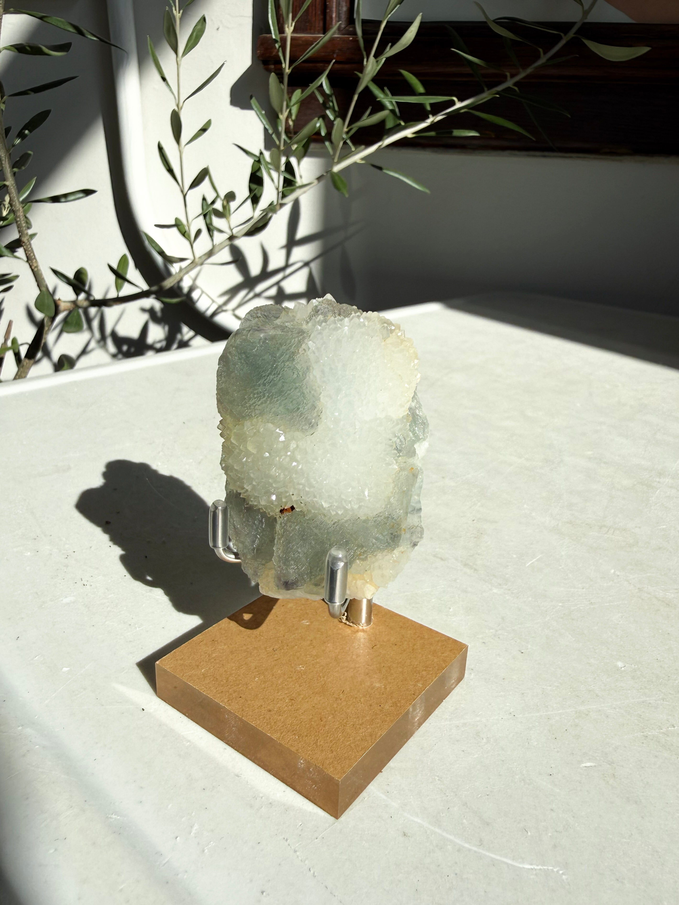 fluorite druzy quartz on wooden and metal stand on marble counter