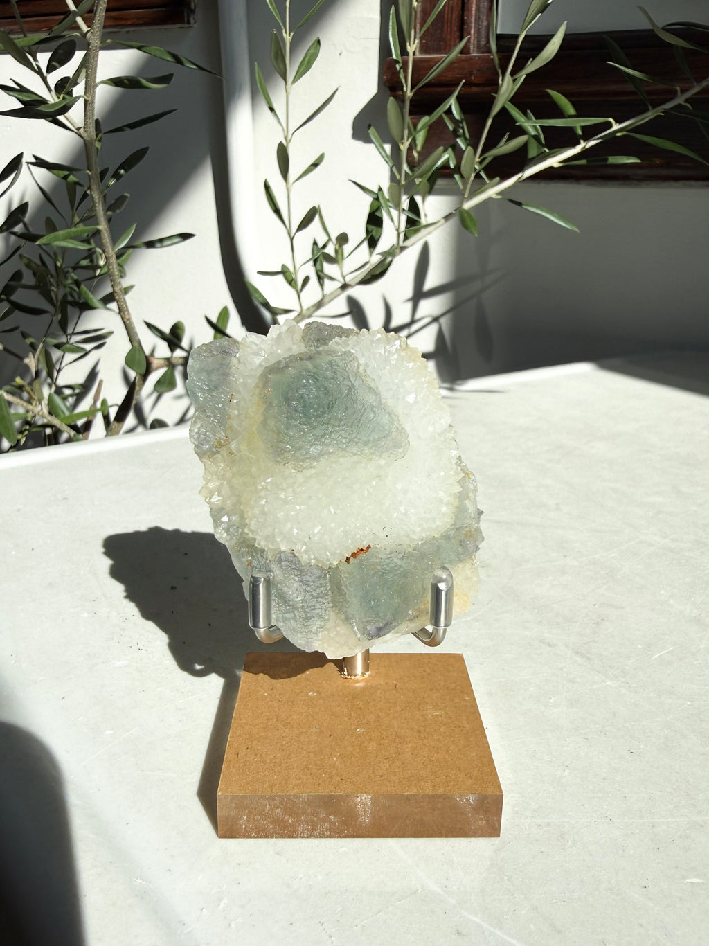 small fujian fluorite druzy quartz on wooden and metal stand on marble counter