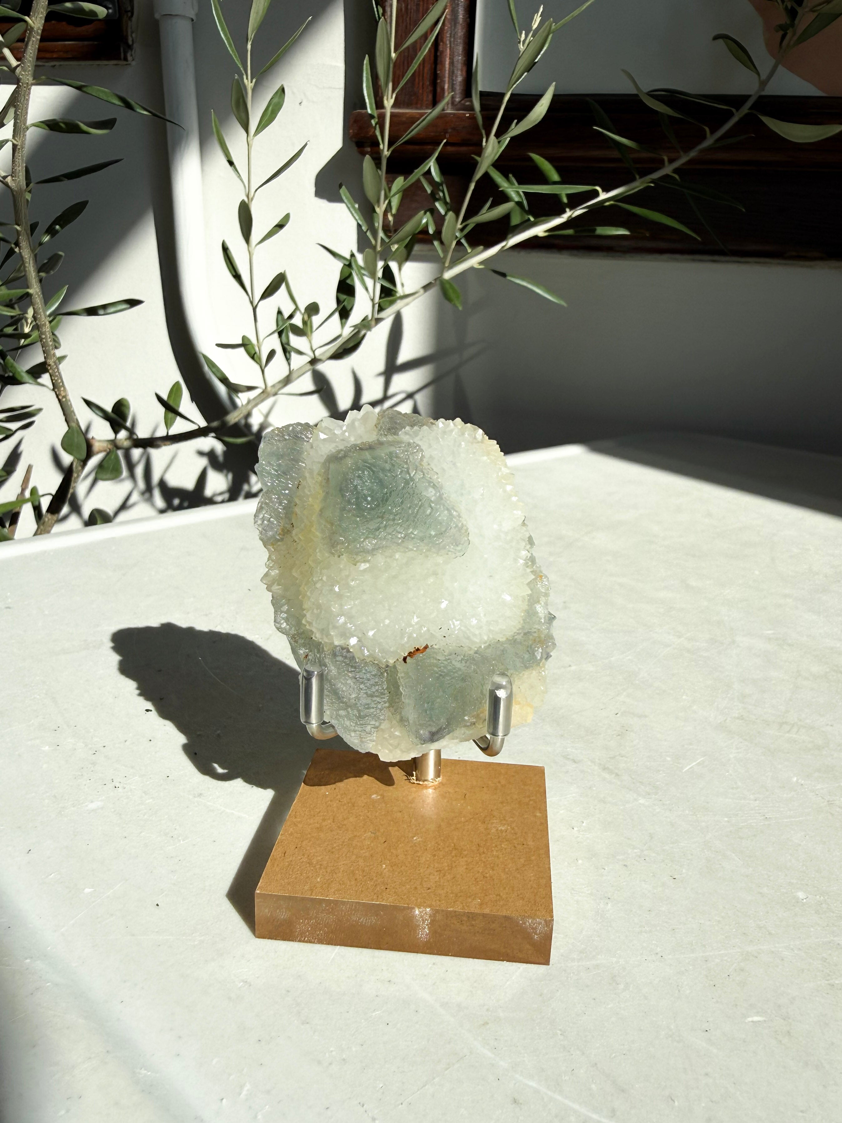 chinese fluorite druzy quartz on wooden and metal stand on marble counter