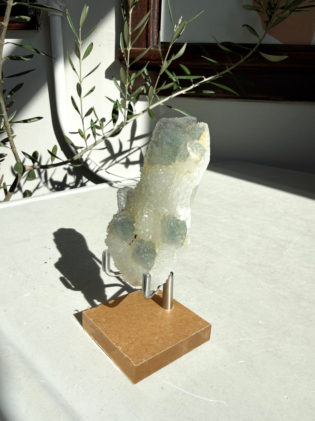 chinese fluorite druzy quartz on wooden and metal stand on marble counter