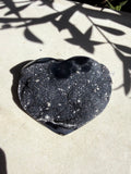 raw navy druzy heart on white counter with foliage shadow
