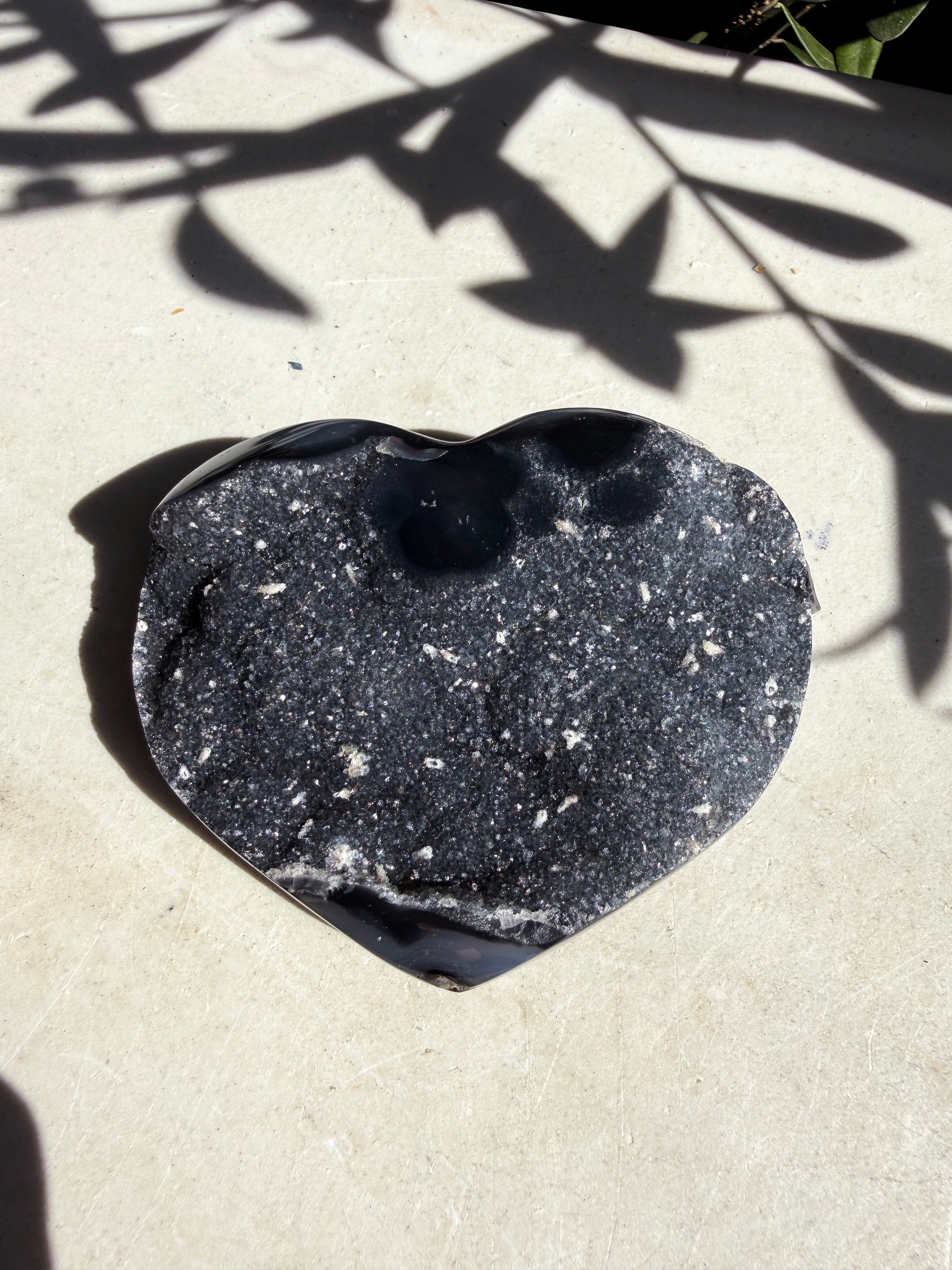 raw navy druzy heart on white counter with foliage shadow