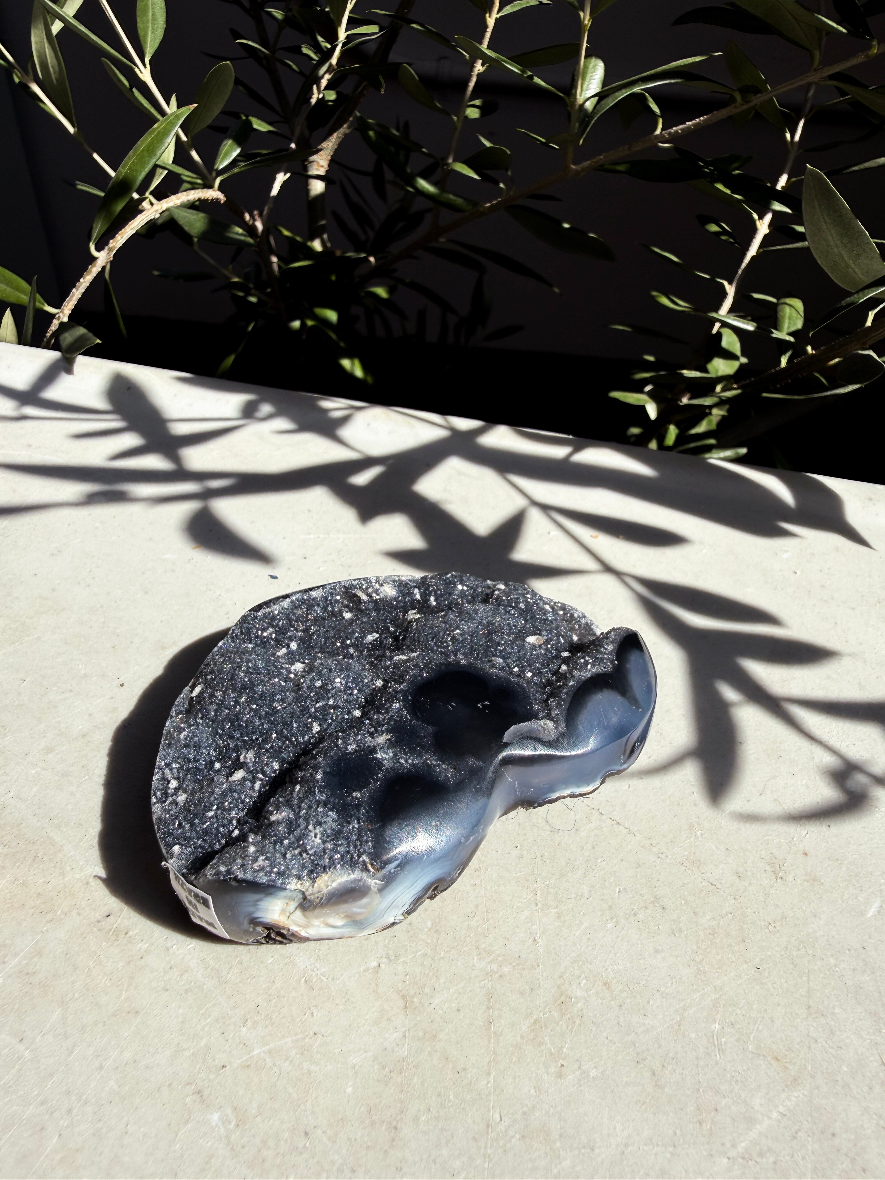 navy druzy heart on white marble counter with foliage and light shadow