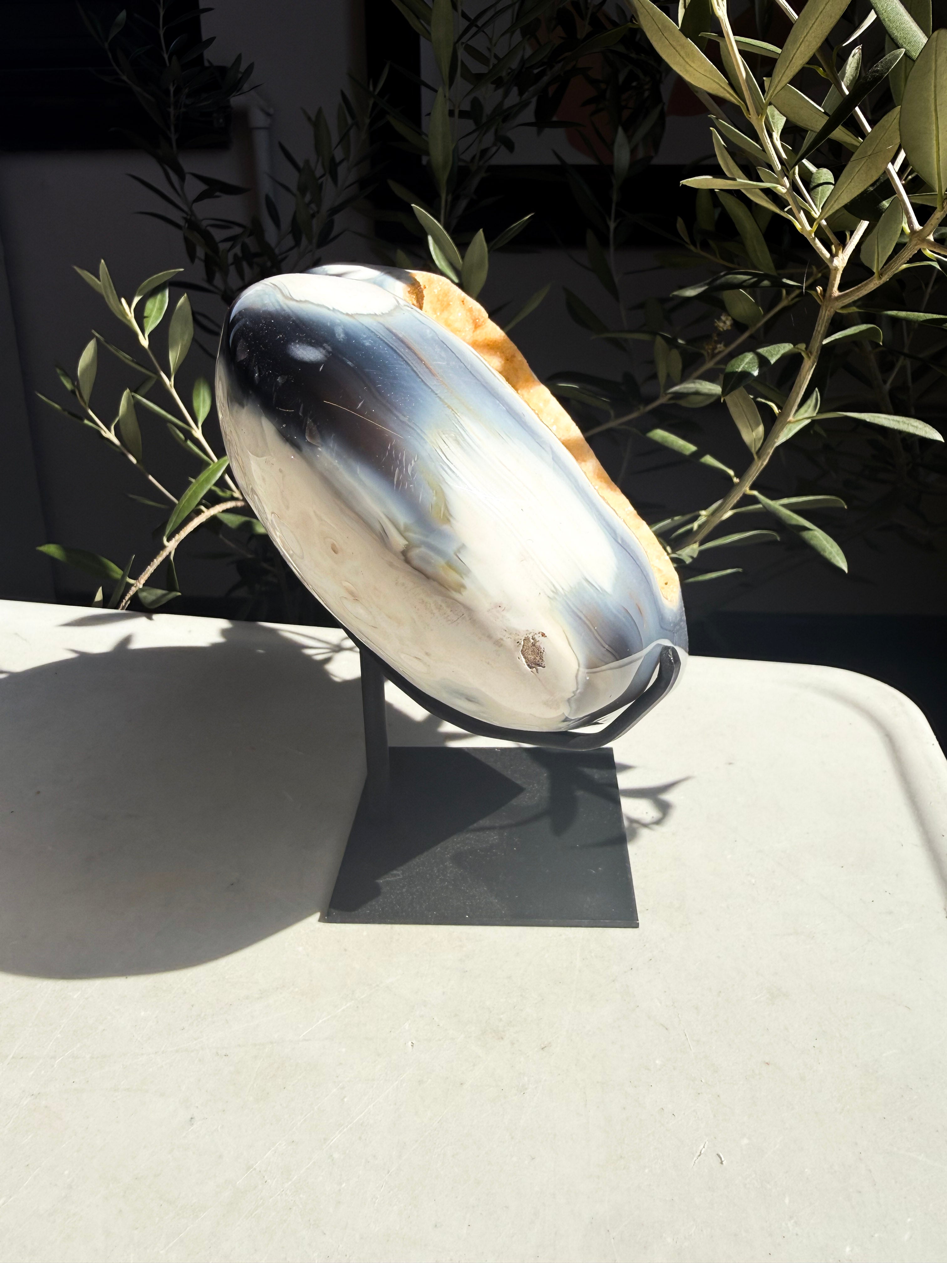 side view of polished orca agate heart with a yellow druzy center