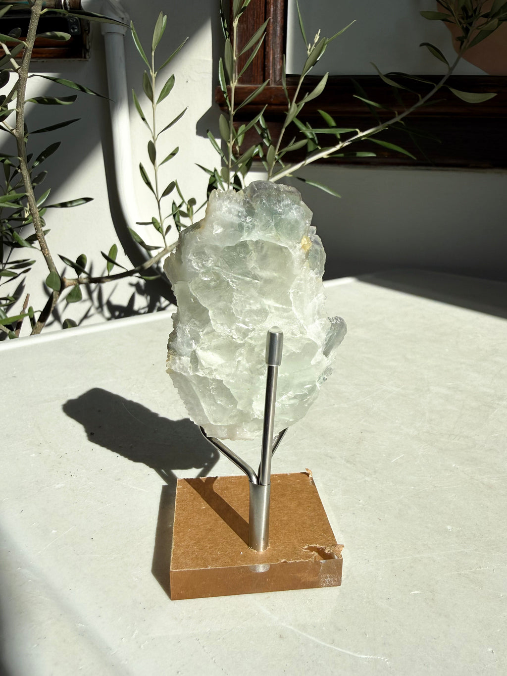 back side of fluorite druzy quartz on wooden and metal stand on marble counter