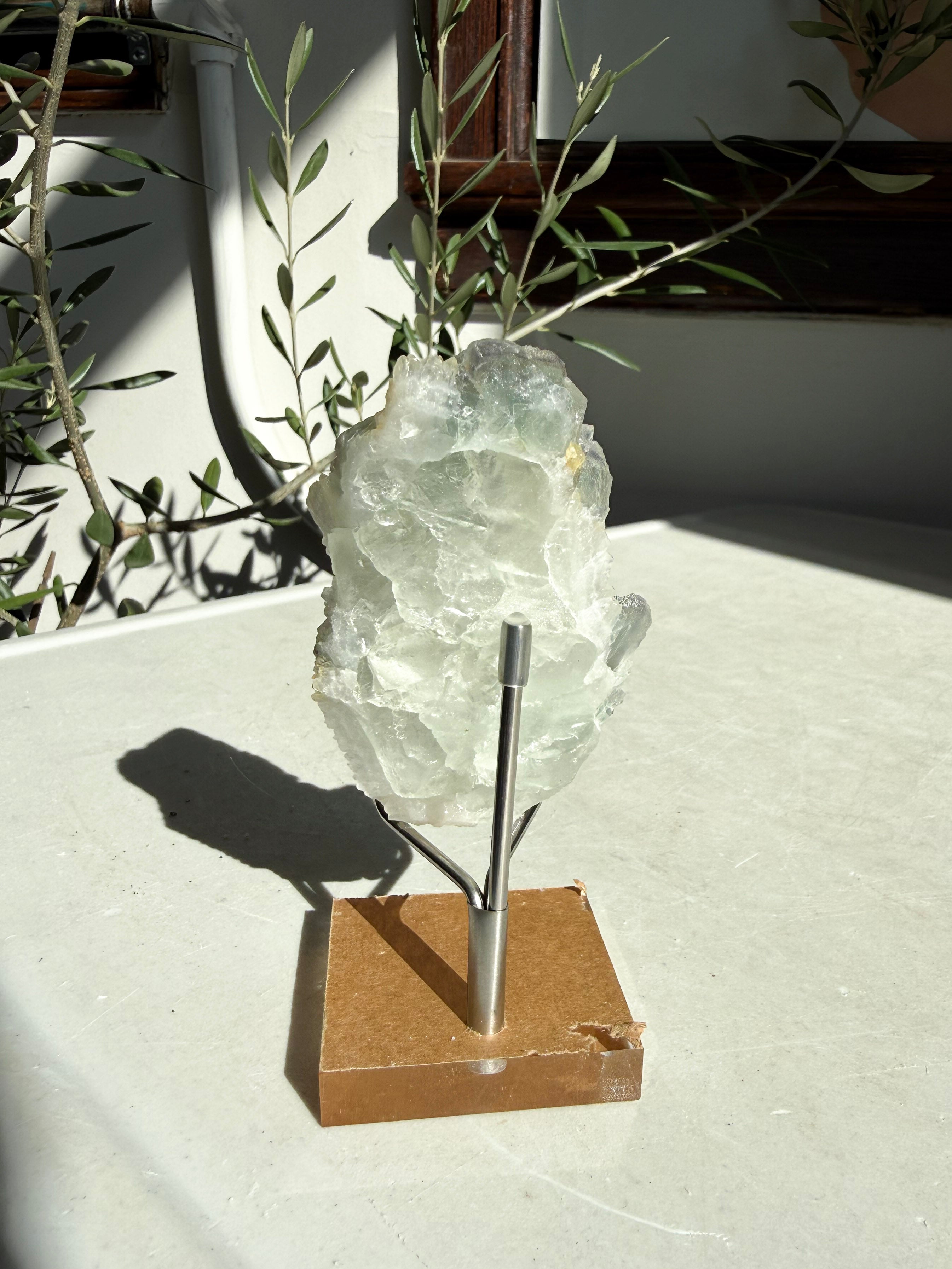 back side of fluorite druzy quartz on wooden and metal stand on marble counter
